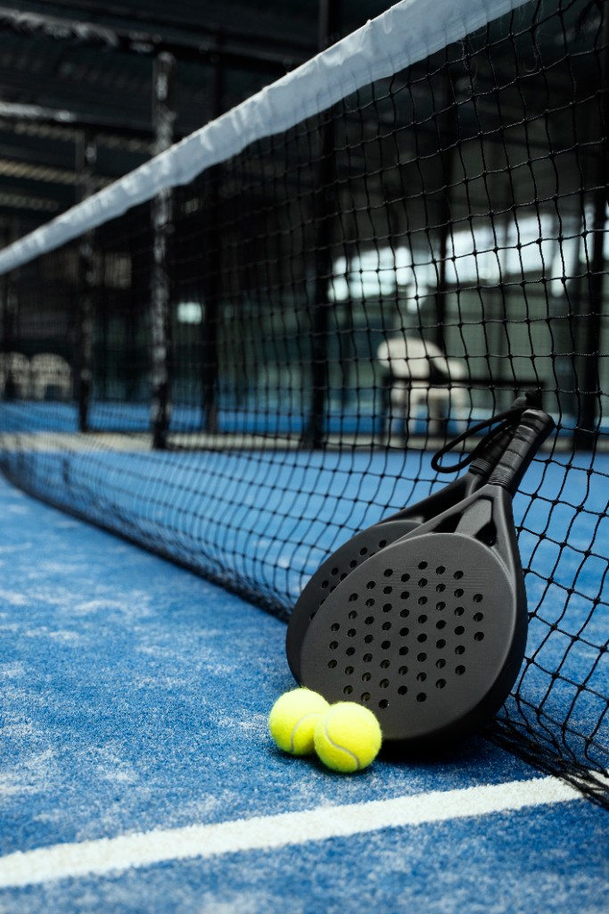 Raquette de padel et balles sur un terrain professionnel